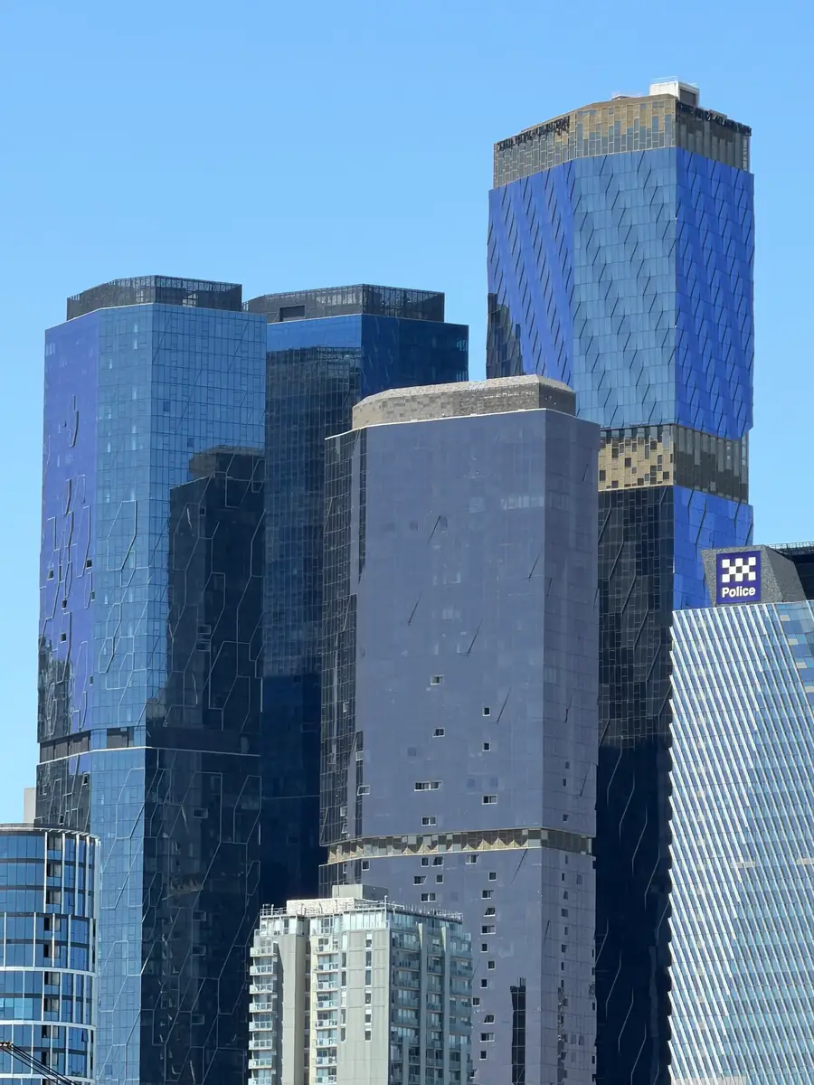Blue-glazed modern high-rise buildings against a clear sky in Melbourne.
